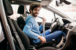 © Westend61 - Smiling man wearing seat belt sitting in car