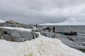 Sticker - Shore of the ocean with people and mountains covered with snow in the background, Antarctica