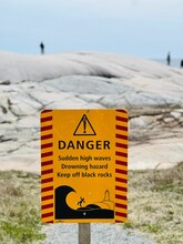 Vertical Closeup Of A Warning Sign To Keep Off Black Rocks At Peggy's Cove, Canada