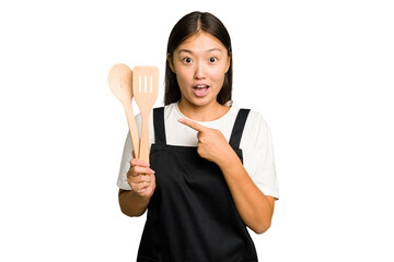 Wall Mural - Young asian cook woman isolated pointing to the side