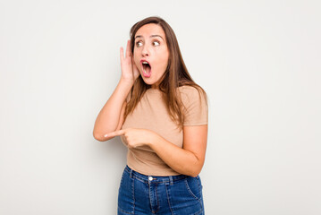 Wall Mural - Young caucasian cute woman isolated on white background trying to listening a gossip.