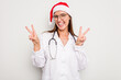 © Asier - Young caucasian doctor woman wearing a santa hat isolated on white background