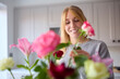 Woman Arranging Bunch Of Flowers On Kitchen Counter In New Home