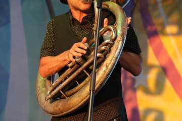 Wall Mural - A man playing a tuba on an outdoor stage illuminated by sunlight.Player in action close-up