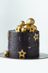 Canvas Print - Luxury cake with dark blue cream cheese frosting decorated with golden chocolate stars and spheres. Birthday space themed cake on the white background