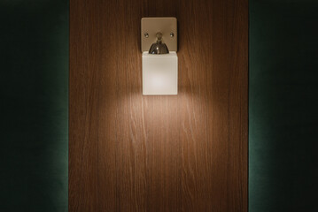 A wall lamp with a yellow shade in the hotel. Bedside light or sconce on the wooden wall of a hotel, hotel or hostel