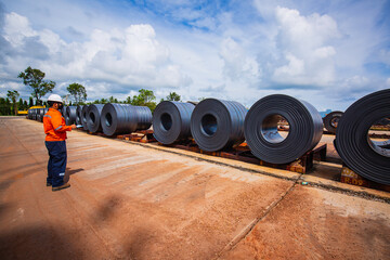 Engineer one worker man inspection on rolls of metal carbon steel sheets outside the factory