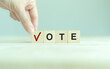 © Parradee - Election vote concept. Vote word with checkmark symbol on wooden cube blocks. Political election campaign logo. Applicable as part of badge design. Voting symbols design. Elections and poll icons.