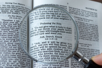 Wall Mural - Magnifying glass over open Holy Bible Book. A close-up. Ask, search, knock verse, Matthew 7:7 Scripture text. Christian biblical concept.