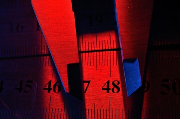 Wall Mural - caliper and metal rulers illuminated in red and blue. close-up