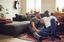 Smiling Adult Gay Couple Sitting On Floor And Talking