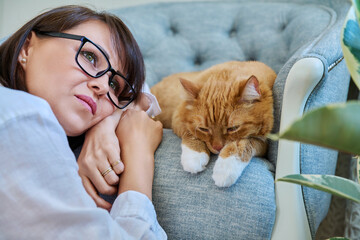 Wall Mural - Middle aged woman with ginger pet cat, home interior background