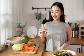 Wall Mural - An Asian young woman drinking fresh water in kitchen at home , healthy lifestyle concept