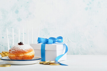 Happy Hanukkah. Hanukkah sweet doughnuts, gift boxes, white candles and chocolate coins on white wooden background. Image and concept of jewish holiday Hanukkah. Top view.