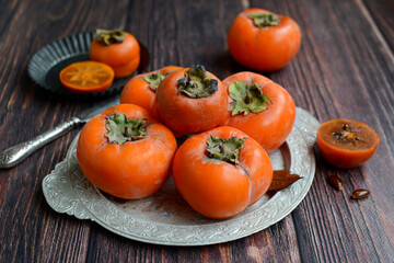 Wall Mural - Sweet juicy persimmon fruits on a rustic background. Autumn, harvest