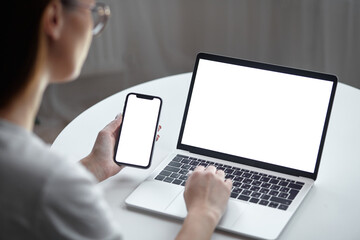 mockup white screen laptop and mobile phone woman using computer while sitting at table at home, bac