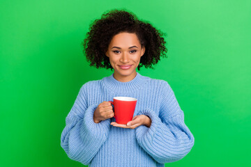 Sticker - Photo of lovely adorable nice friendly girl with wavy hairstyle dressed blue pullover holding cup isolated on green color background