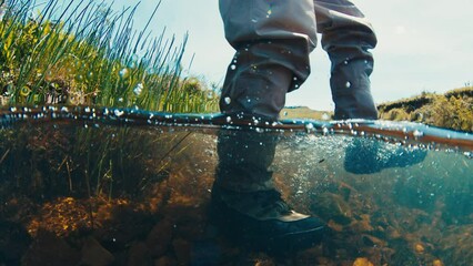 Wall Mural - Fisherman underwater view. Angler walks in the wading boots on the slippery rocky bottom of a rapid river