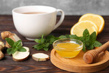 Fototapeta  - Bowl with honey for tea, lemon, mint and ginger on wooden table