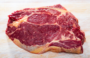 Canvas Print - Close up of uncooked beef chop on wooden background