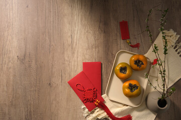 Wall Mural - Persimmons, lucky money, lucky ornaments on a wooden table. Empty space. traditional new year's background with fruits and new year's items. space for text 