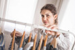 © kostikovanata - Young beautiful woman stands near the closet and hangs up her clothes. Clothes storage.