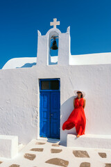 Wall Mural - Vertical view of red dressed woman in Oia