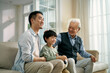 © imtmphoto - asian son father grandfather watching soccer game on TV together at home