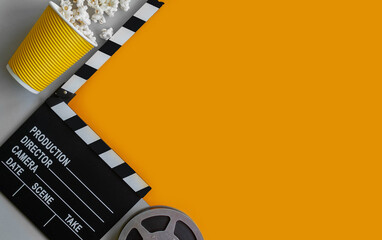 stylish mockup with clapperboard,film reel and popcorn in black and orange colors. copy space, space for text. top view. flat lay style. concept cinema party, film industry, movie premiere