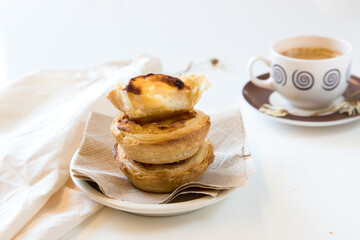 Pasteis de nata, traditional sweet of Portuguese cuisine. Small crunchy puff pastry pies and a cream made with eggs. Often tasted and accompanied with coffee. On white background, copy space.