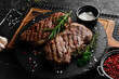 © Yaruniv-Studio - Two juicy rib eye steak, herbs and spices. On a black stone background.