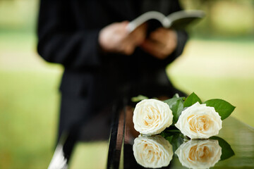 closeup of two white roses on coffin at outdoor funeral ceremony, copy space