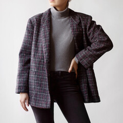 Wall Mural - Woman wearing grey turtleneck, oversized check blazer and black jeans isolated on white background