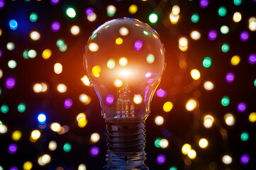 Vintage glowing light bulb  on colorful,  sparkling lights background