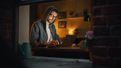 Aufkleber - Professional Male Programmer Writing Code for New Project and Working Remotely on Laptop From Home Office. Freelance Software Engineer Designs App From his Apartment. View From Outdoors into Window.