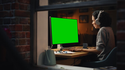 Aufkleber - Female Designer Using Desktop Computer with Green Screen Chroma Key Monitor. Remote Access Manager Listening to Music or Podcast in Headphones, Freelancer Working at Night. Into the Window Shot.