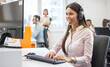 Smiling female helpline operator with headset in call center.