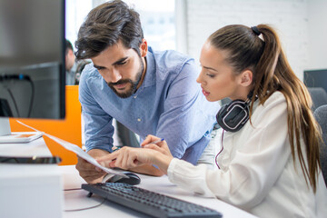 Businesswoman and businessman examining document together at call center office.