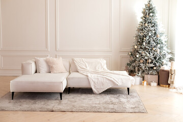 Wall Mural - Comfortable couch with three cushions and a blanket standing in bright room interior with grey carpet in a modern interior. Modern interior living room with large light corner sofa and Xmas tree.	