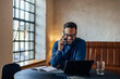 © bnenin - Busy man working at his office while making a phone call and smiling.