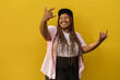© VISTA by Westend61 - Happy woman showing horn sign gesture in front of yellow wall
