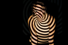 Woman With Spiral Illuminated Pattern On Body Against Black Background