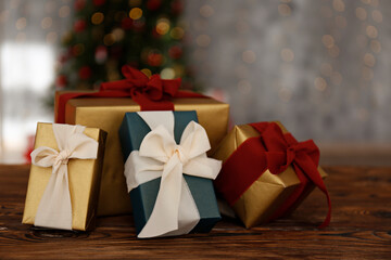 Wall Mural - Close up shot of presents in colorful wrapping. Christmas tree with soft yellow lights, bokeh effect background. Traditional new year holiday decoration, intimate lighting. Close up, copy space.