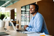 © Drobot Dean - Indian businessman in headphones working on laptop computer in office