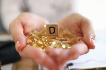 Wall Mural - Close-up of woman hands holding many vitamin D capsules.