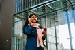 © Drobot Dean - Cheery woman using mobile phone and headphones while walking through city street