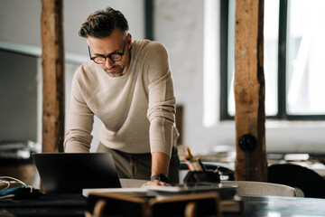 Wall Mural - White middle-aged man working with laptop in modern office