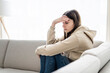 © Louis-Paul Photo - teen sitting on couch at home Frustrated confused female feels unhappy problem in personal life