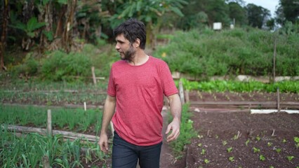 Wall Mural - Young man walking in small farm agriculture. Happy person walks in community farm smiling