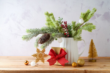 Wall Mural - Christmas decoration with pine tree branches in vase, gift box  and golden ornaments on wooden table over bright background